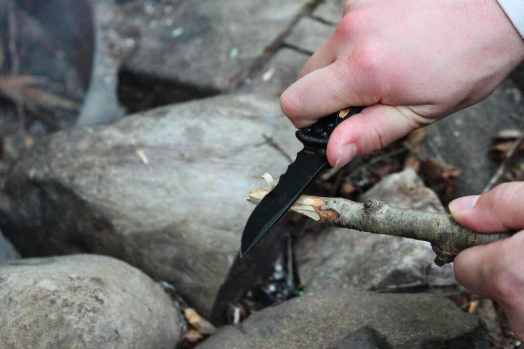 The CRKT Drifter Pocket Knife being used to shave down a roasting stick