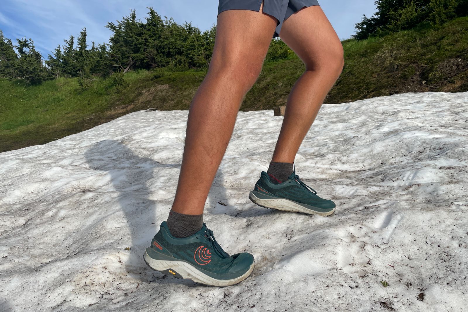 A man hikes up a snow patch in the mountains.