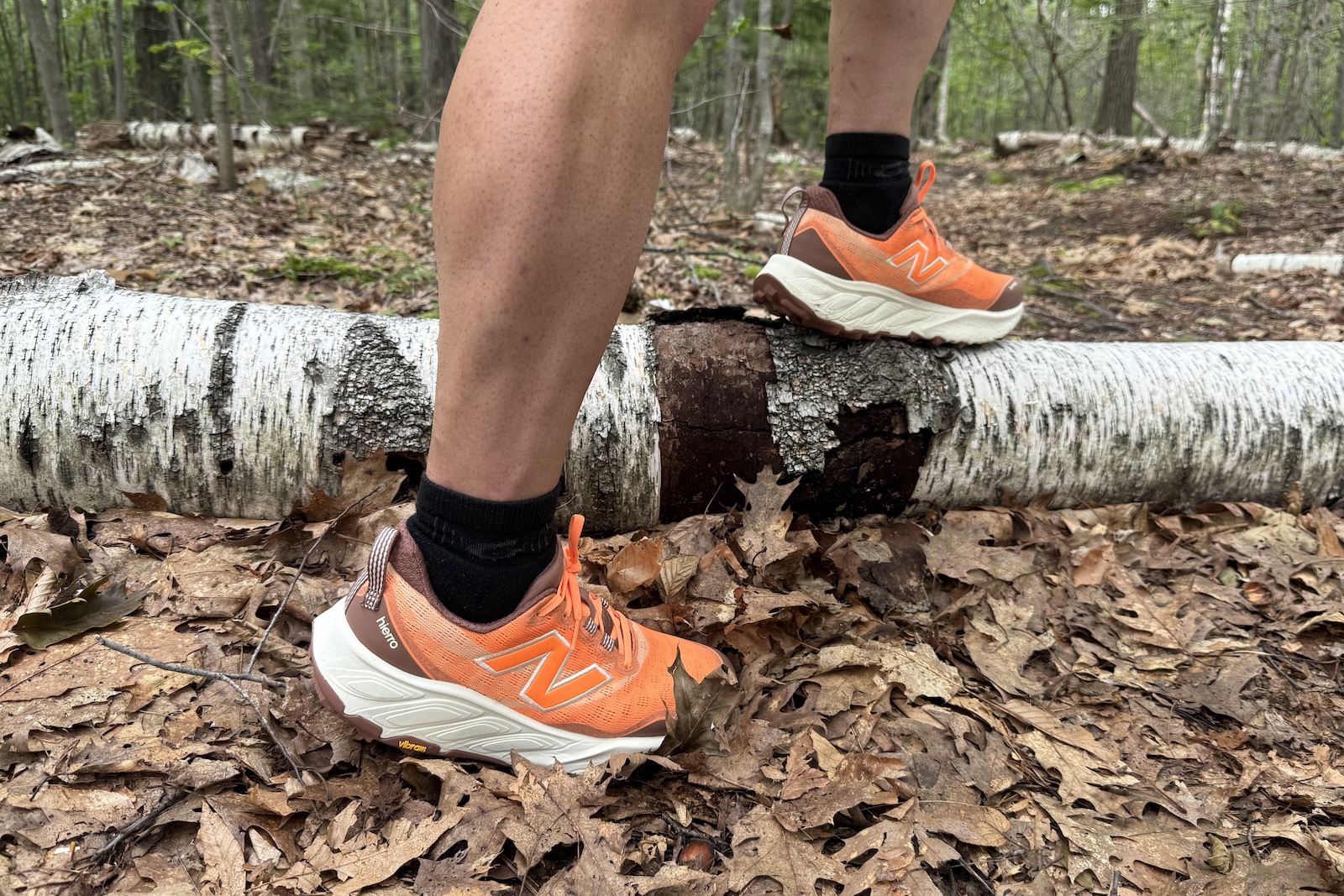 Close up of orange New Balance Fresh Foam Hiero 9 with a birch tree