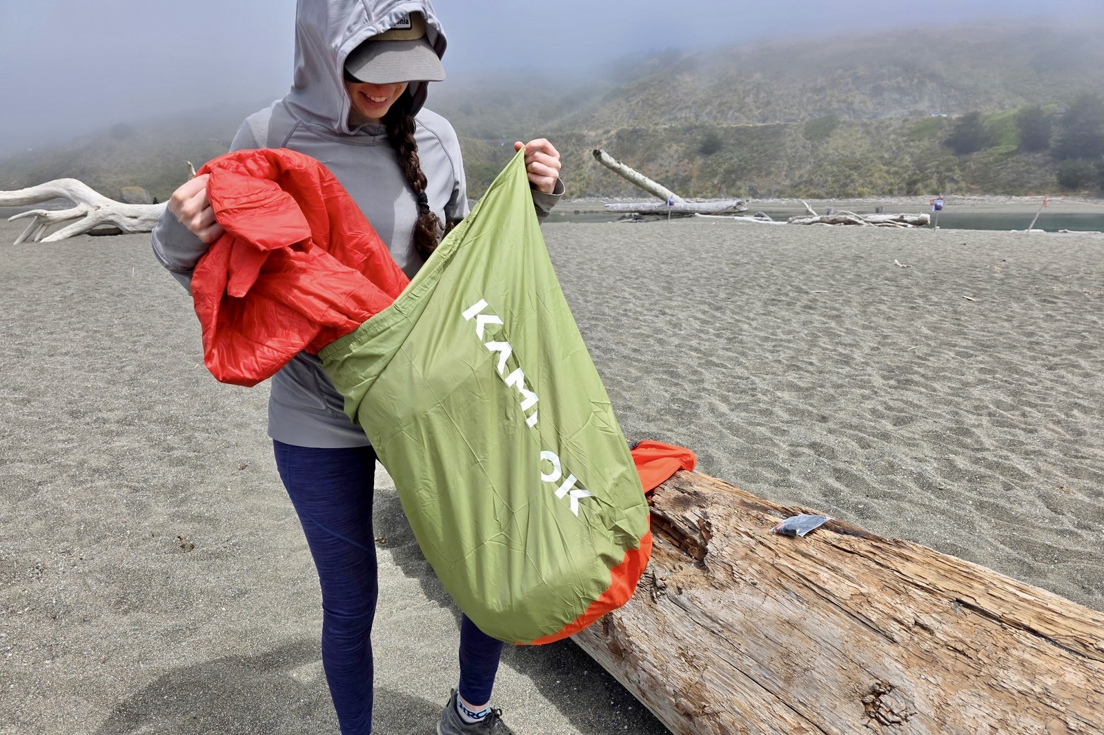 A woman pulls a blanket out of a large, loose sack.