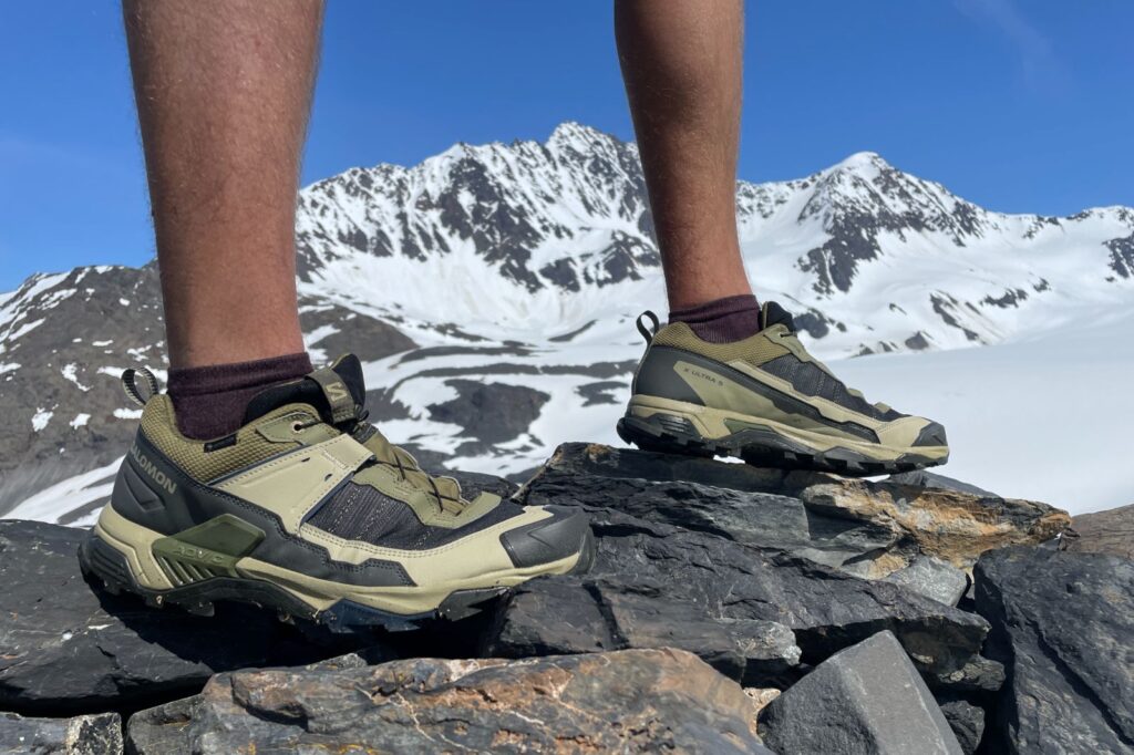 A closeup of hiking shoes in front of a glacier.