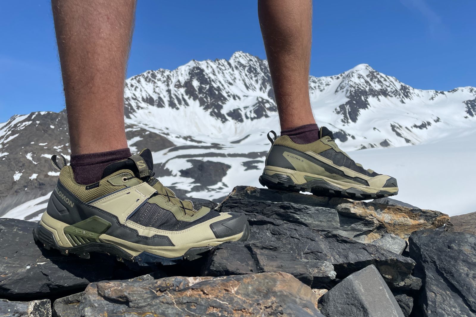 A closeup of hiking shoes in front of a glacier.