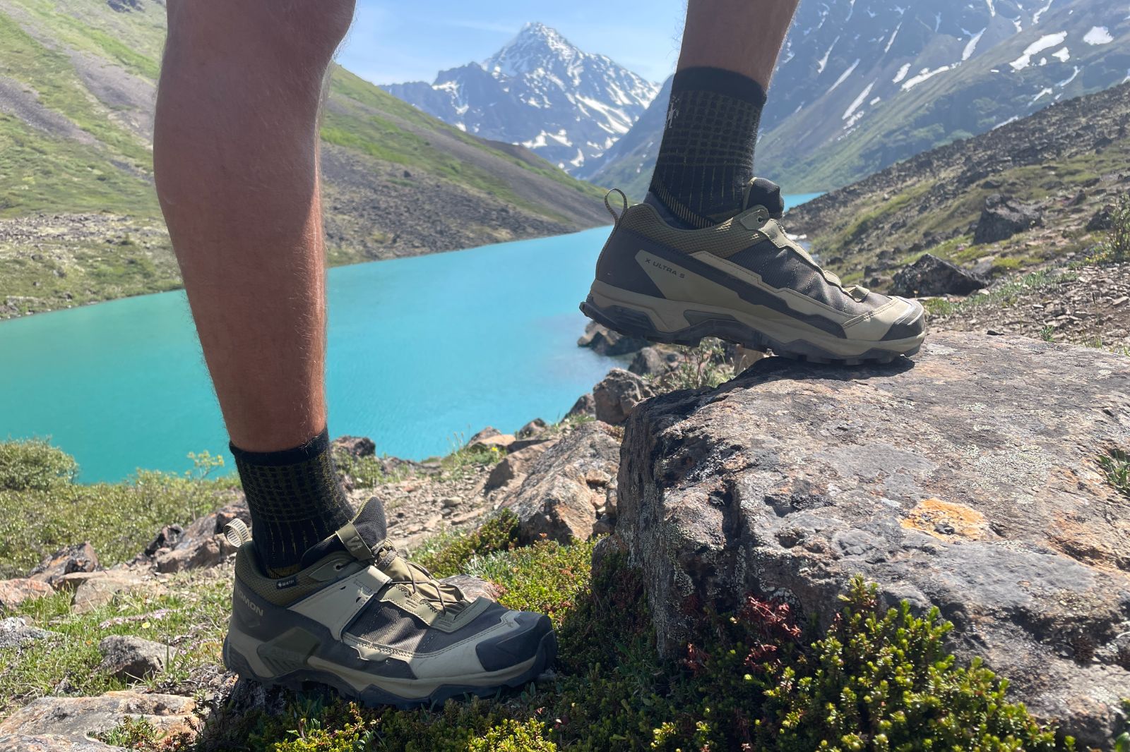A closeup of shoes in front of an alpine lake.