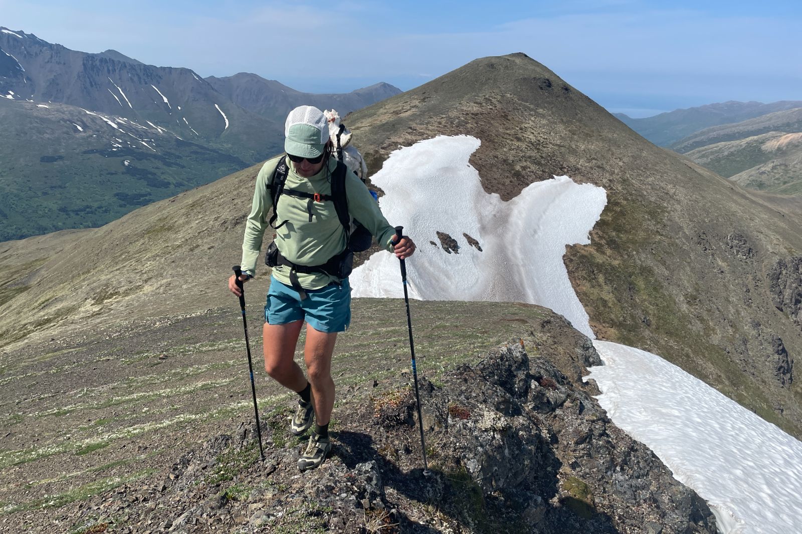 A man hikes along an alpine ridgeline.