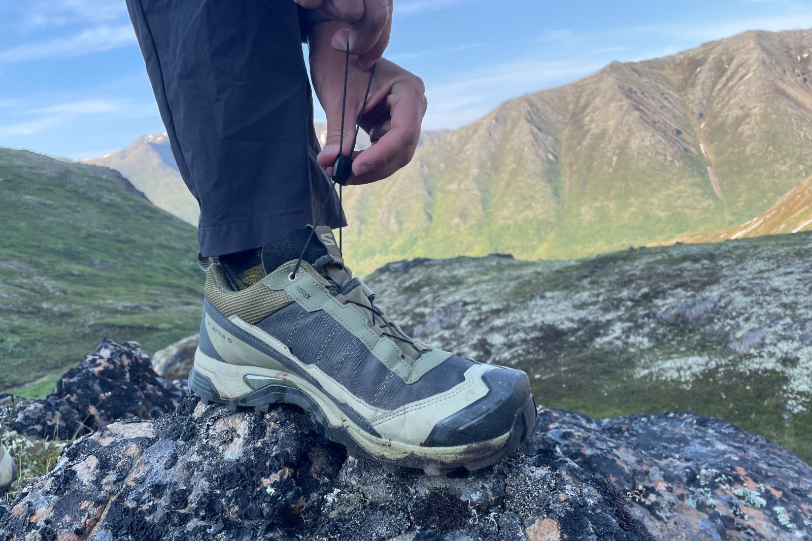 A man tightens the laces of his hiking shoes.