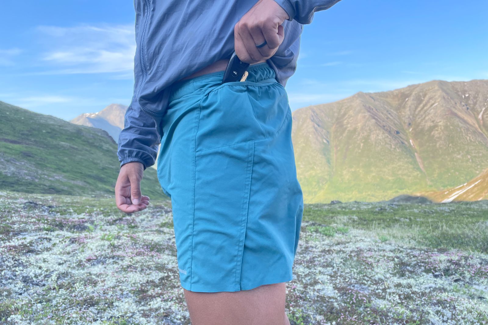 A man puts car keys in small pockets on a pair of shorts.