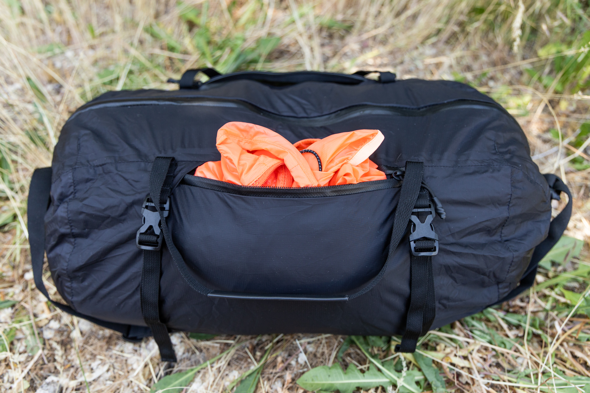 A jacket peeks out of the solid water resistant pocket on one side of the Matador Freefly Packable Duffel.