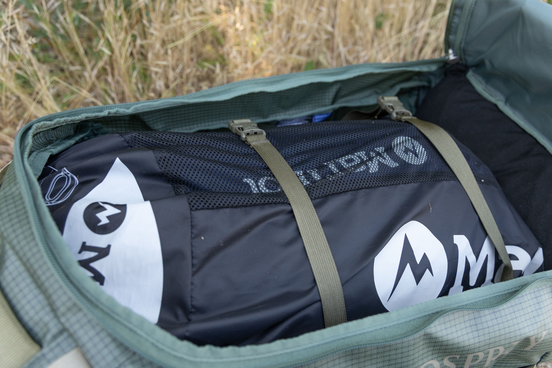 An interior view of the Osprey Transporter duffel shows a sleeping bag secured with interior compression straps.