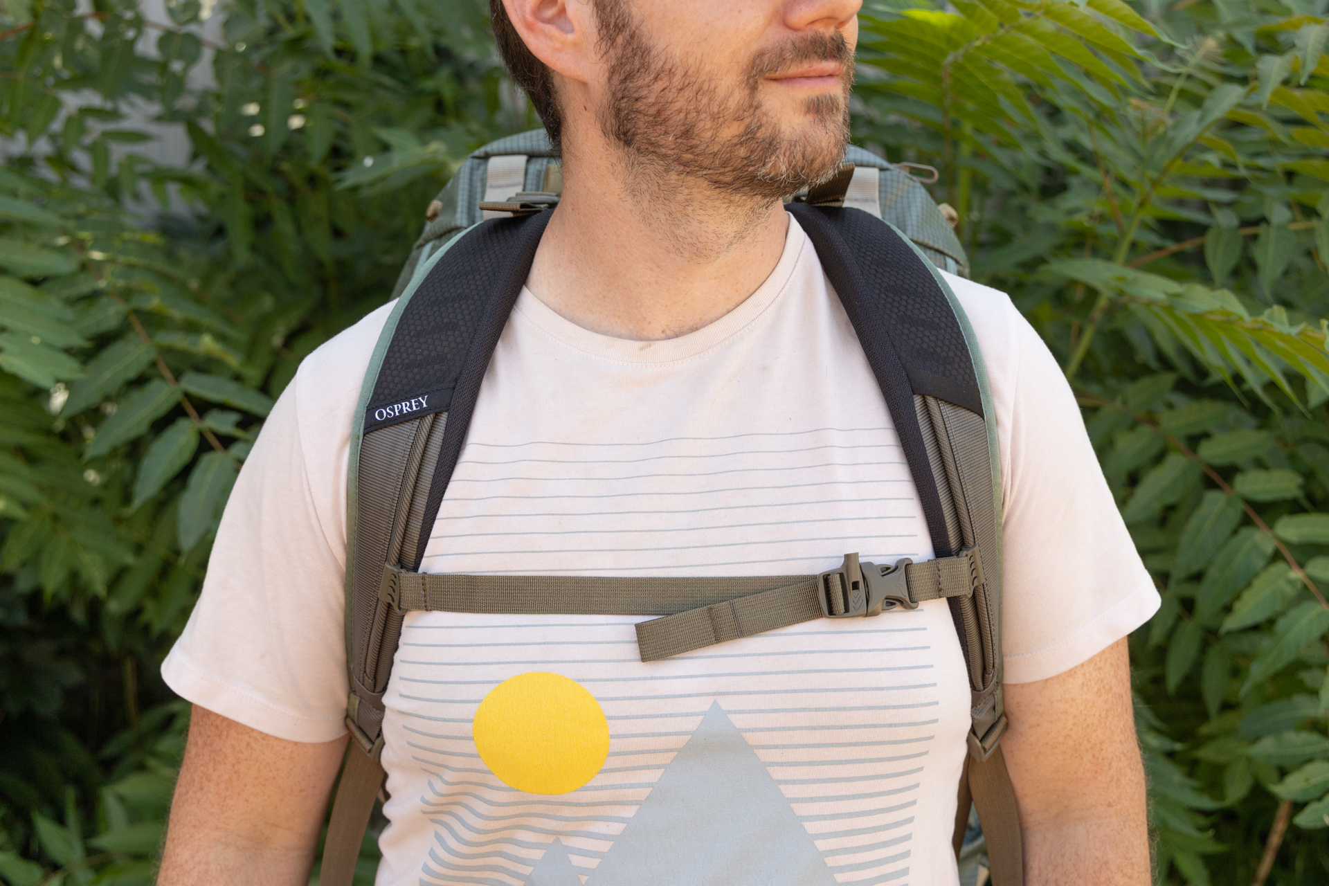 A front view of a man wearing the Osprey Transporter duffel as a backpack. The straps sit comfortably on his shoulders and the sternum strap is buckled.
