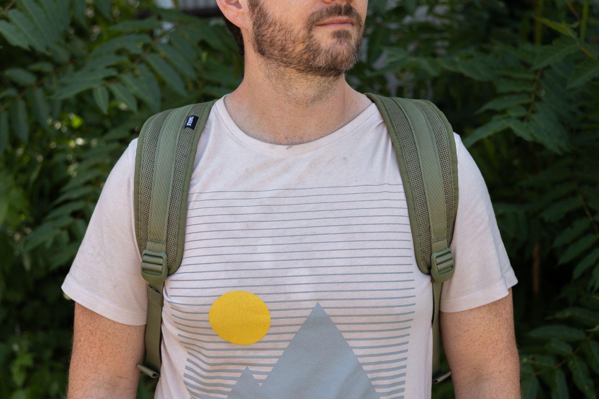 A man wears the Thule Chasm 40L as a backpack. You can see the wide padded straps from the front.