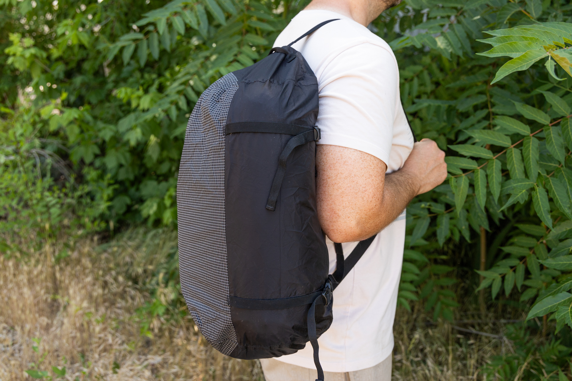 A man carries the Matador Freefly Packable Duffel over his shoulder with the back resting flush against his back using the adjustable shoulder strap.