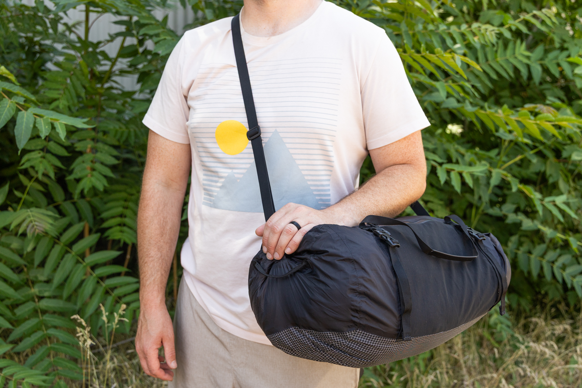 A man carries the Matador Freefly Packable Duffel cross-body using the adjustable shoulder strap.