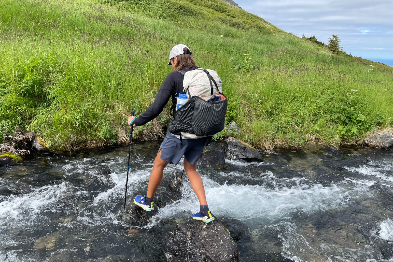A man crosses a river while backpacking.