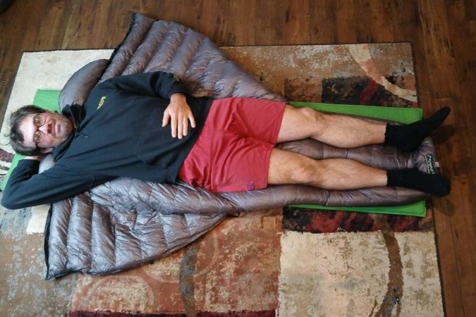 The Western Mountaineering AstraLite Quilt with a person for scale