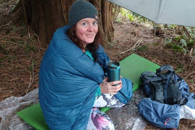 Hammock Gear Burrow 20 Quilt wrapped around someone drinking coffee in camp