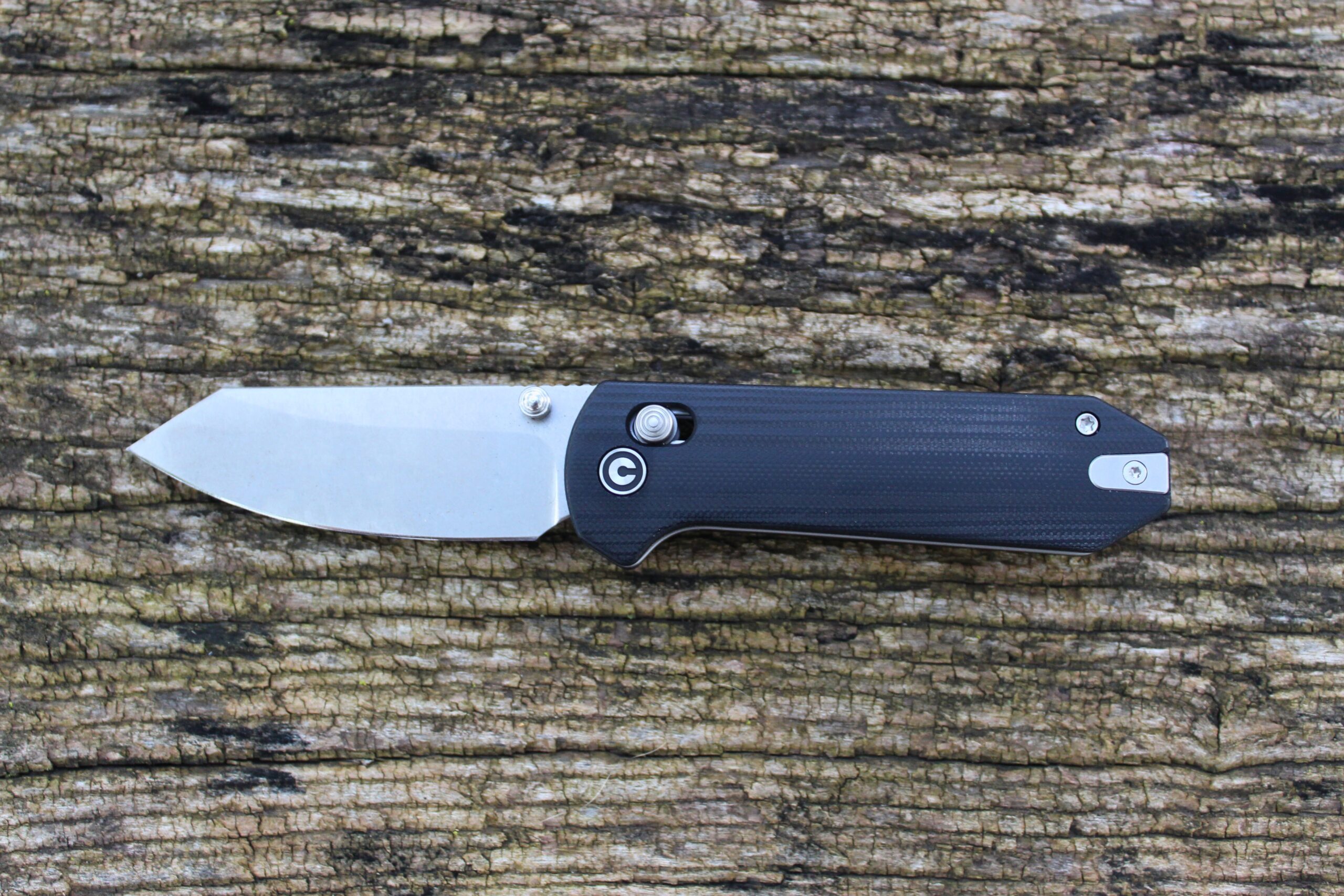 The Civivi Yonder G10 Pocket Knife open sitting on a backdrop of wood