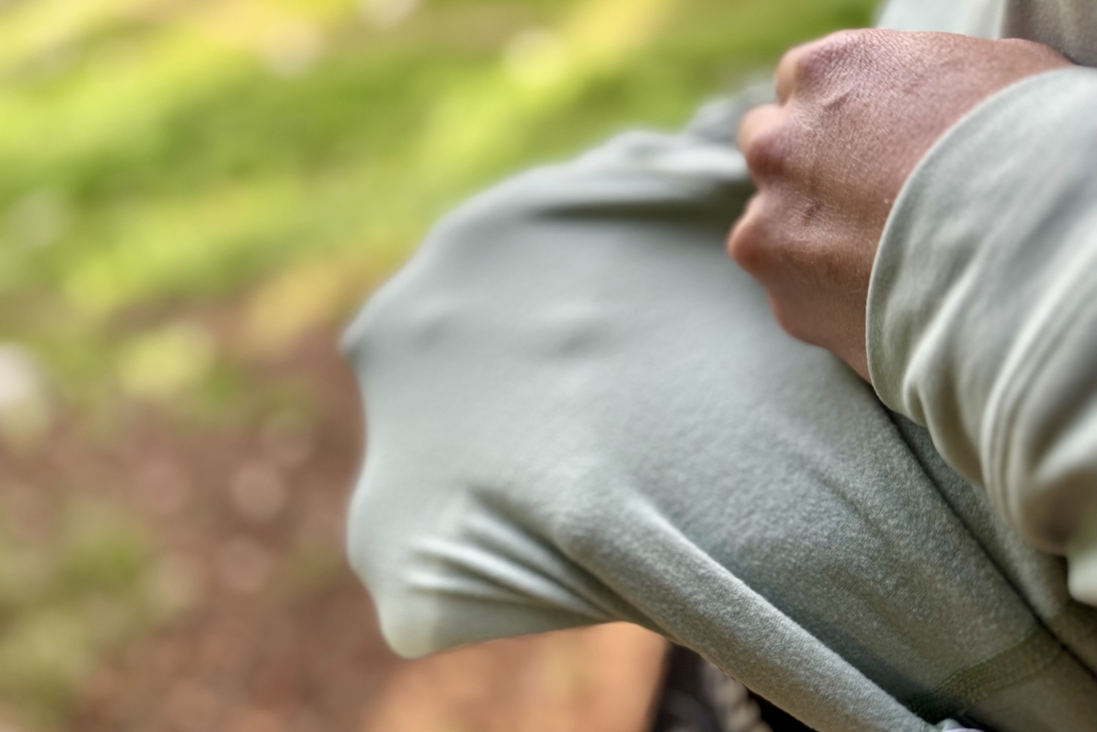 A hiker turns shows the inside fabric of her light blue base layer