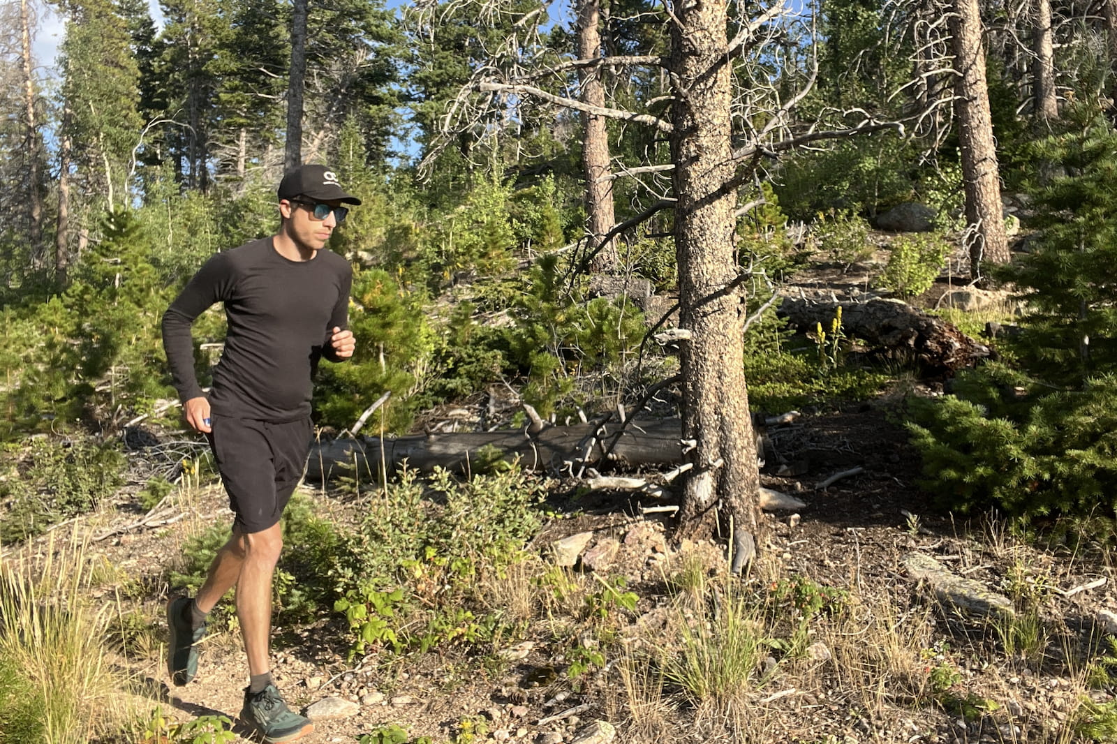 a runner runs along a wooded trail in a black base layer.