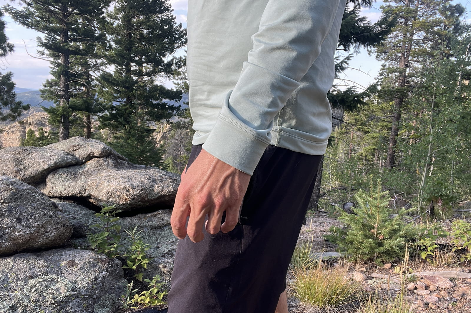 a closeup profile from chest to knees of a hiker wearing a light blue base layer.