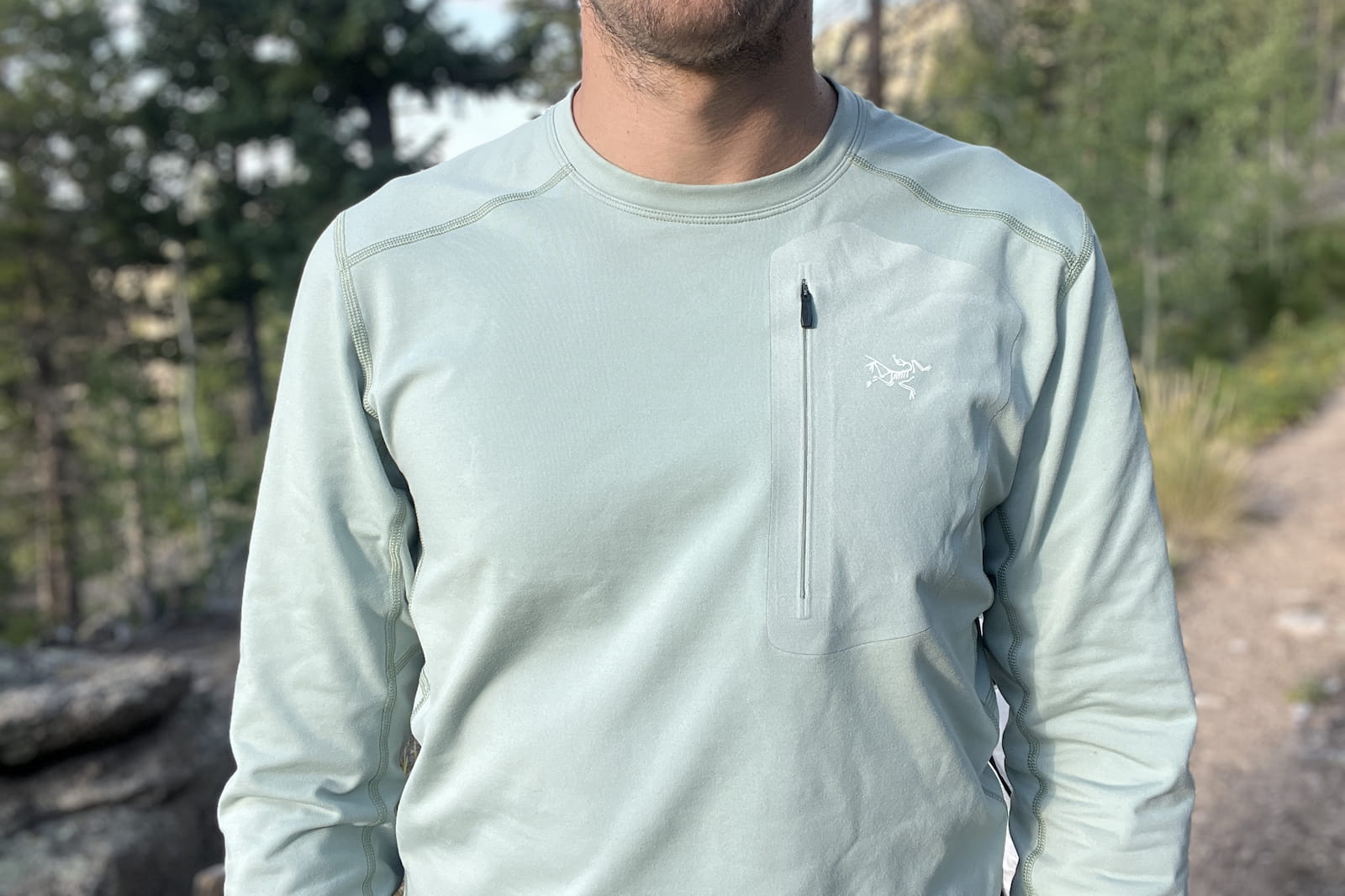 a front torso shot of a hiker in the woods wearing a light blue base layer.