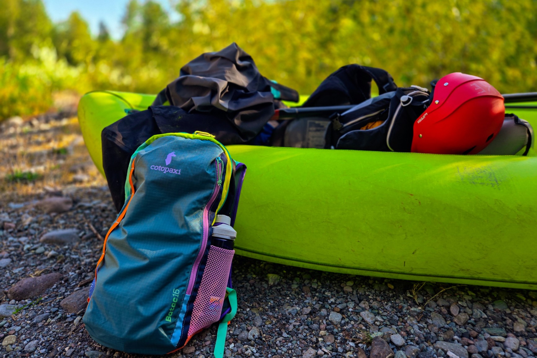 Colorful Cotopaxi daypack leans against a colorful (lime green) inflatable kayak.