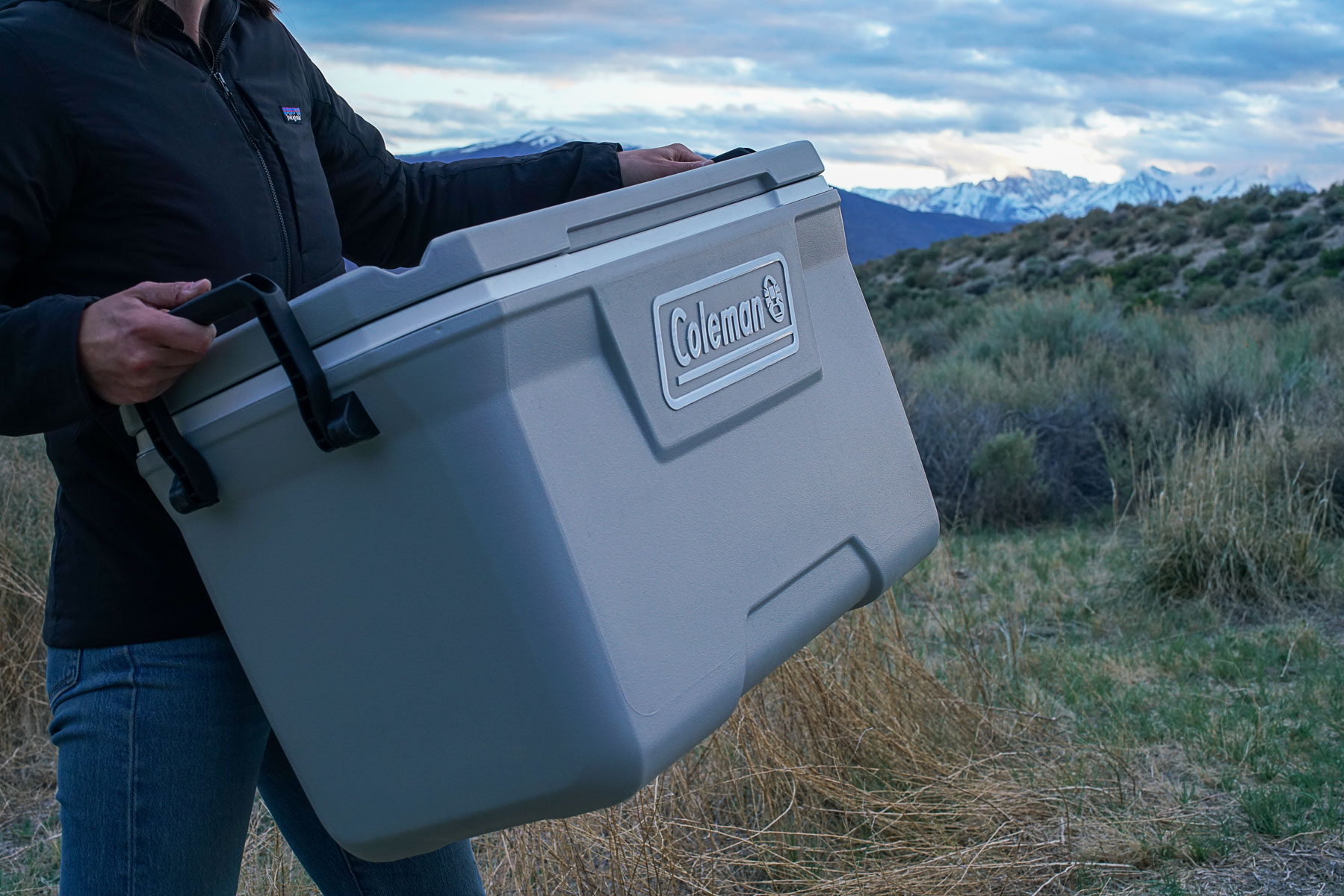 A close up of a person carrying the Coleman 316 Series 70QT cooler.