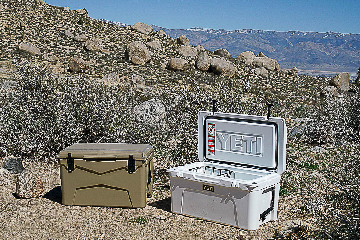 The XSpec 60QT sits on the ground next an open YETI Tundra 65 cooler. There are boulders and mountains in the background.