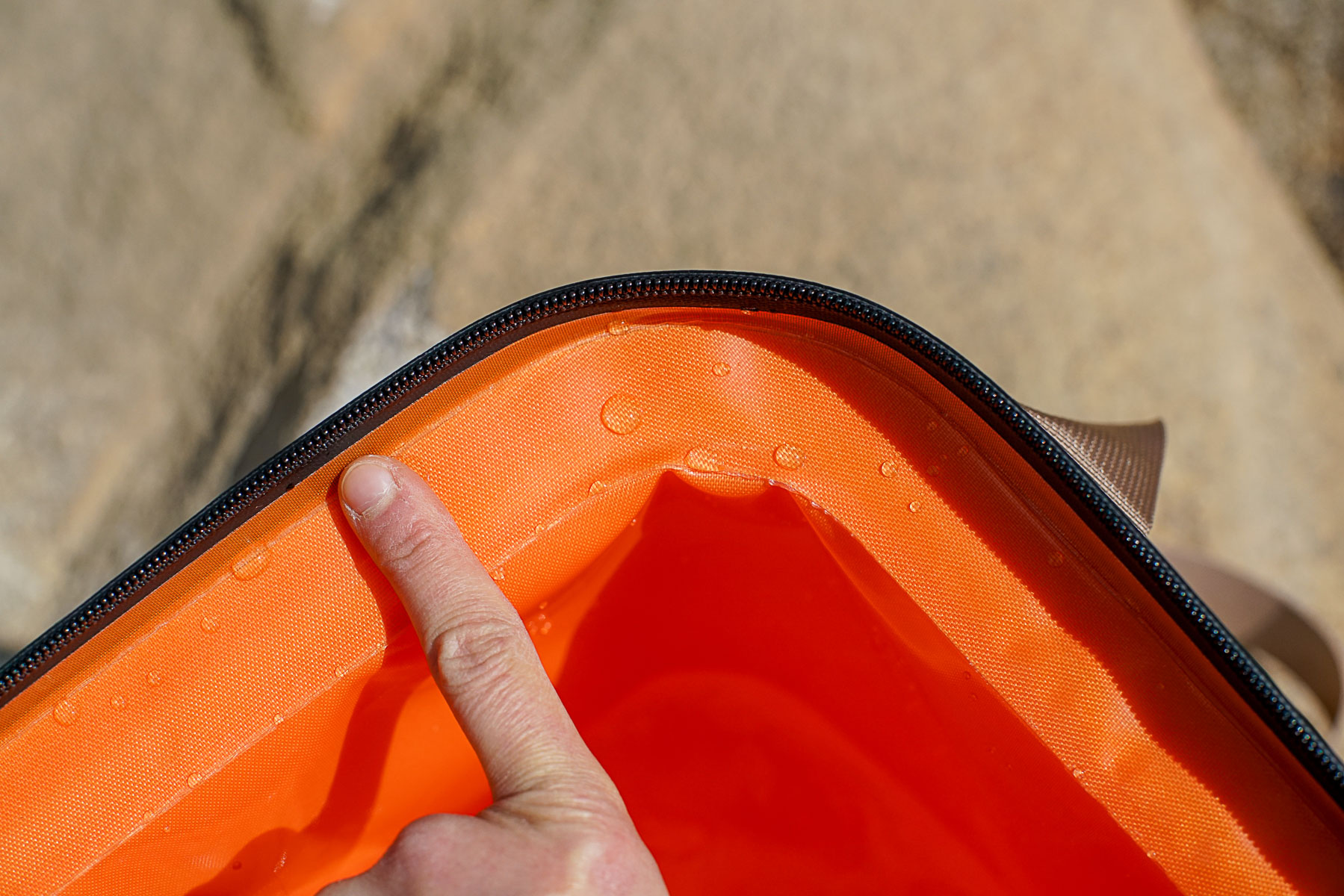 A close up of a corner of the RTIC Soft Pack cooler with a human finger providing scale for the cooler's layer of insulation.