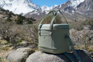 The Hydro Flask Carry Out 20L cooler sits on a rock with mountains in the background.