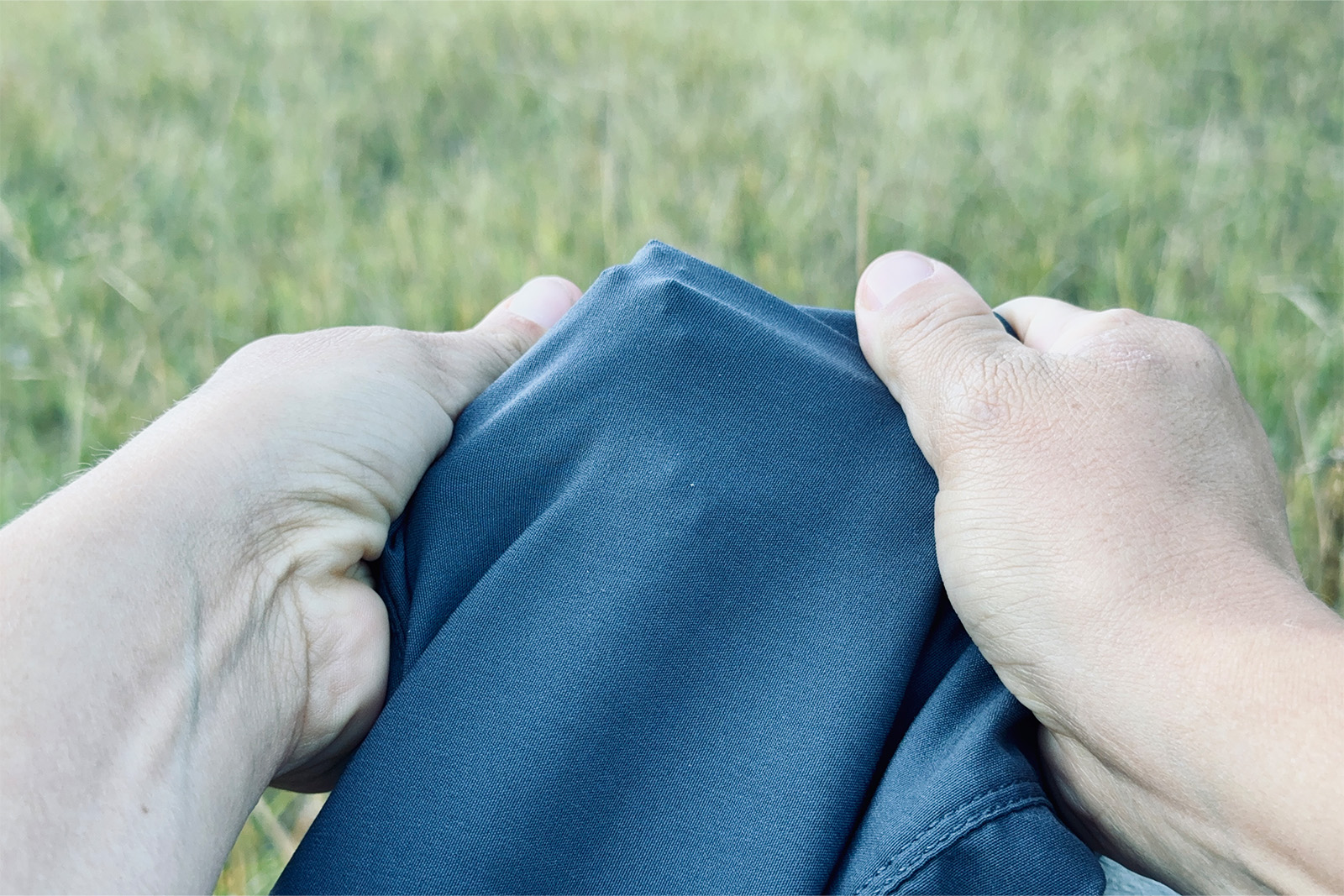 Close up of hands stretching the Duluth pants over a sharp stick.
