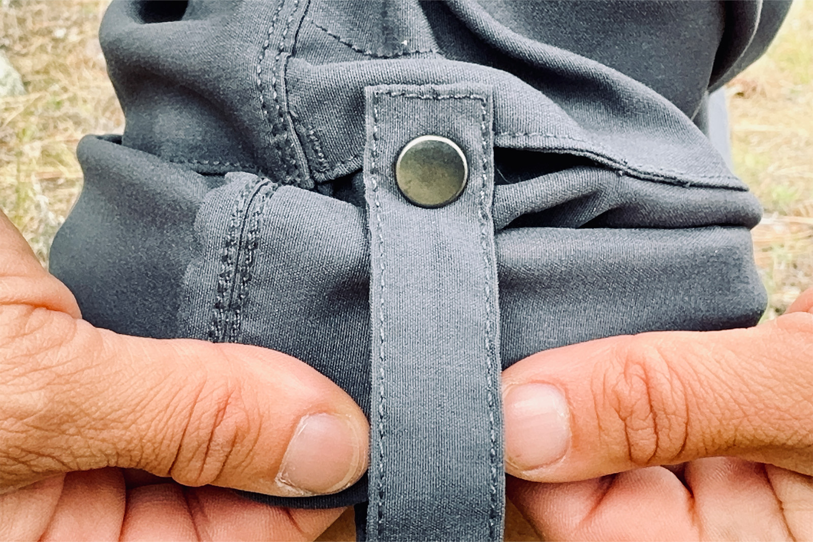 Close up of two hands holding the rolled up Duluth pants cuff with the snap features shown prominently.