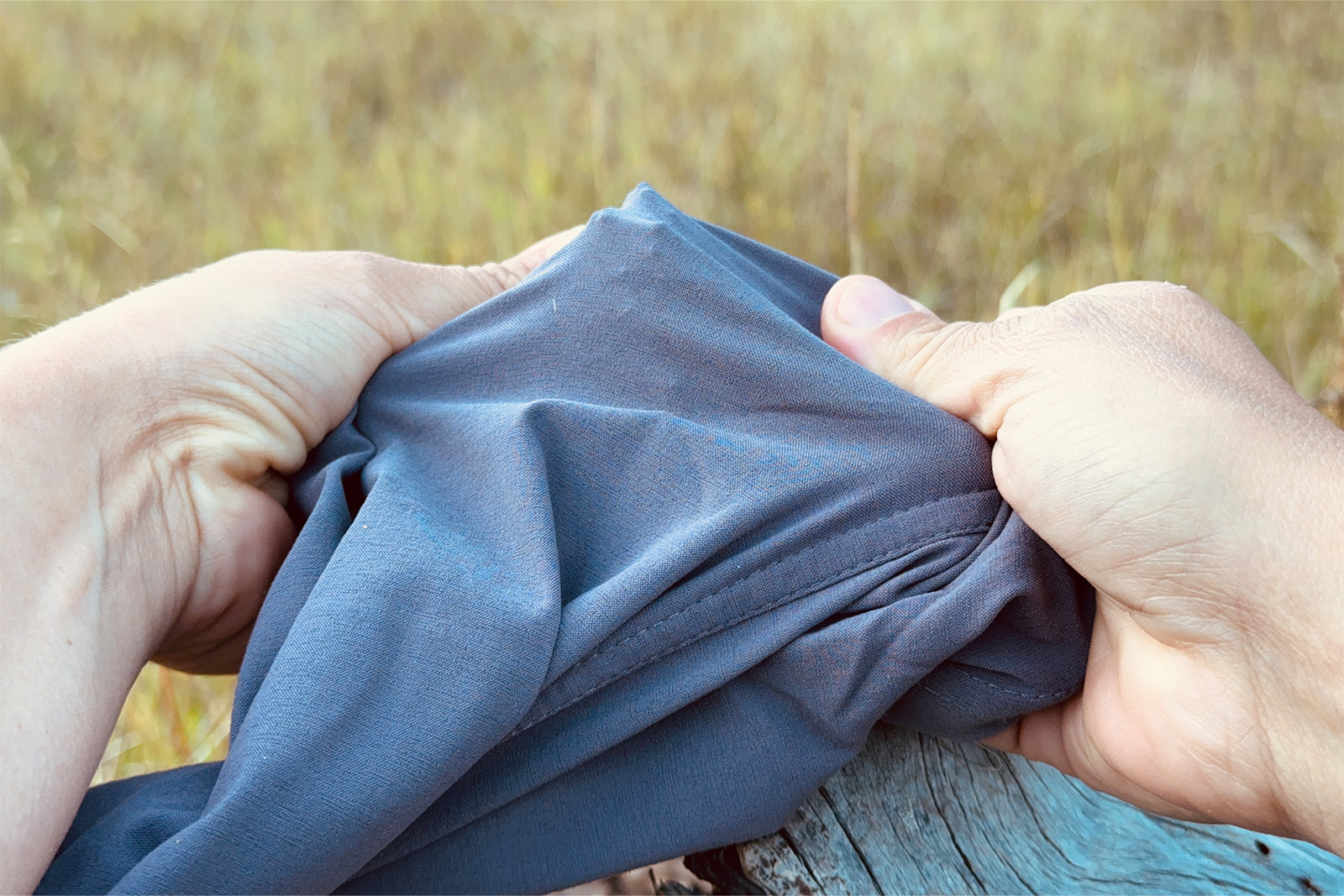 Close up of hands stretching the Dynama pants over a sharp stick.