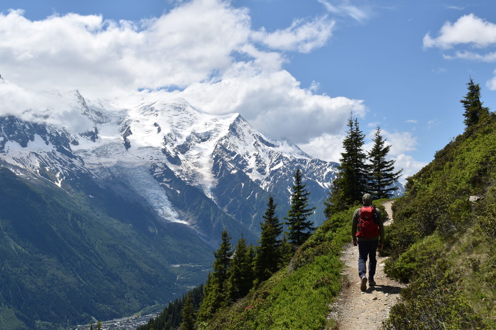 A male hike walks toward the horizon across the valley from snowcapped Mt Blanc