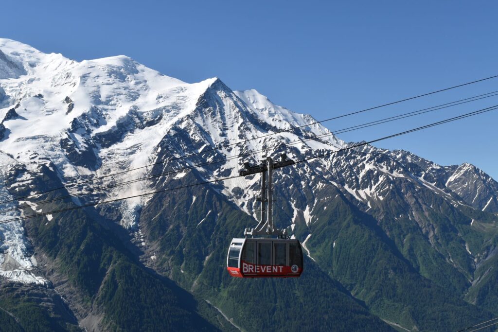 A red cable car descends a mountain above Chamonix, France
