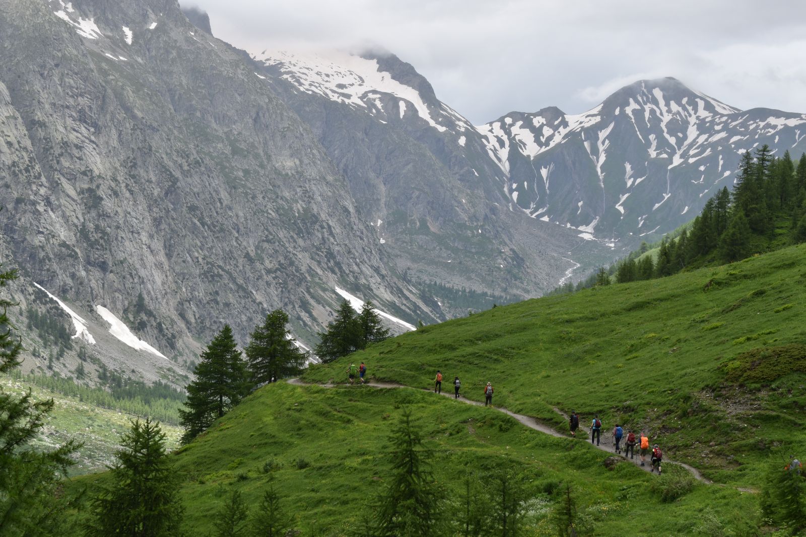 A dozen hikers spread out across a short segment of the TMB trail