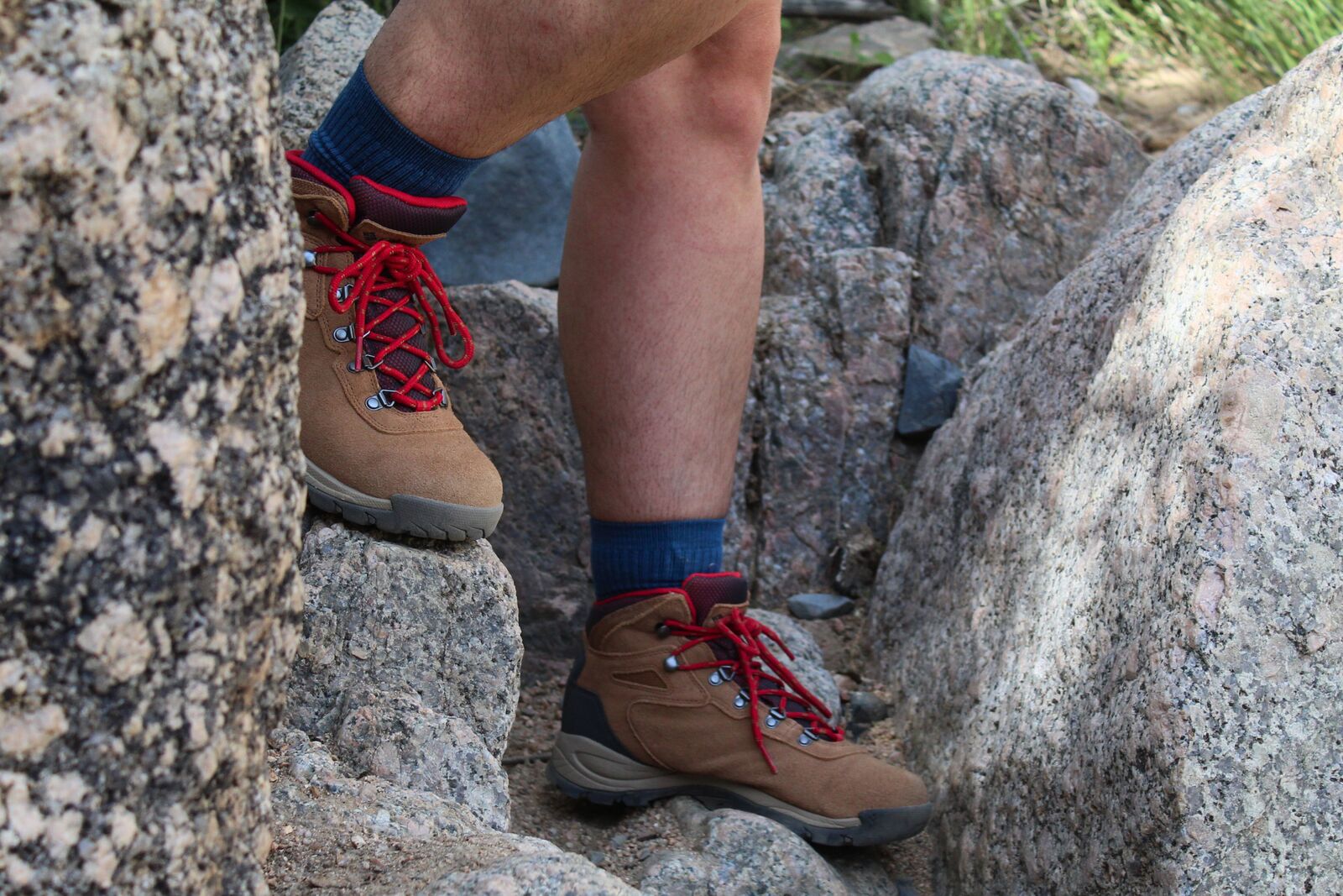 Hiker walking down rocks wearing the Columbia Newton Ridge Plus Waterproof Amped