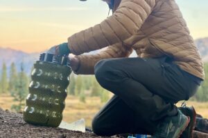 a hiker kneels to pack a bear canister