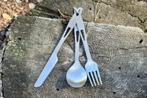 a 3-piece cutlery set sits on a tree stump