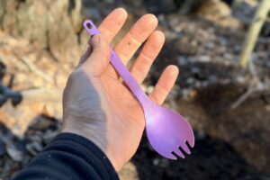 a hand holds a purple titanium spork