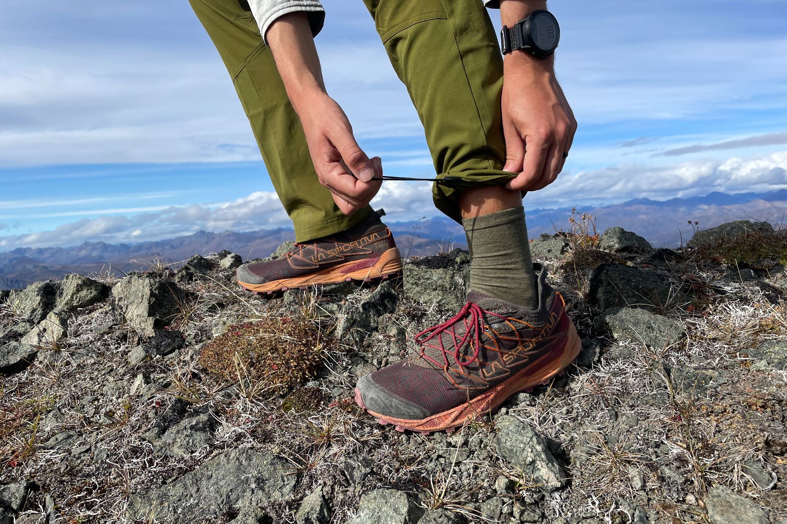A closeup of a man tightening the cuffs on his pants with an elastic cinch.