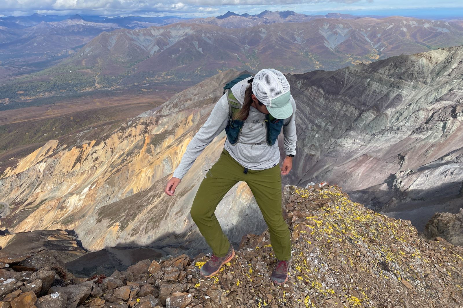 A man walks along a narrow ridgeline in the alpine.