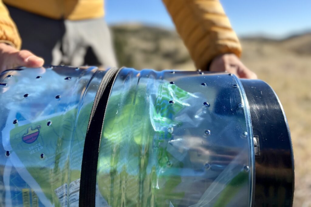 a closeup of a strap going over the top of a blue bear canister