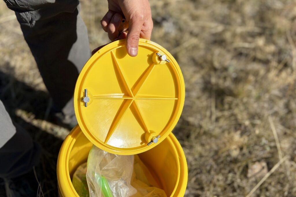 a hiker shows the under side of a lid for a bear canister with three locking points
