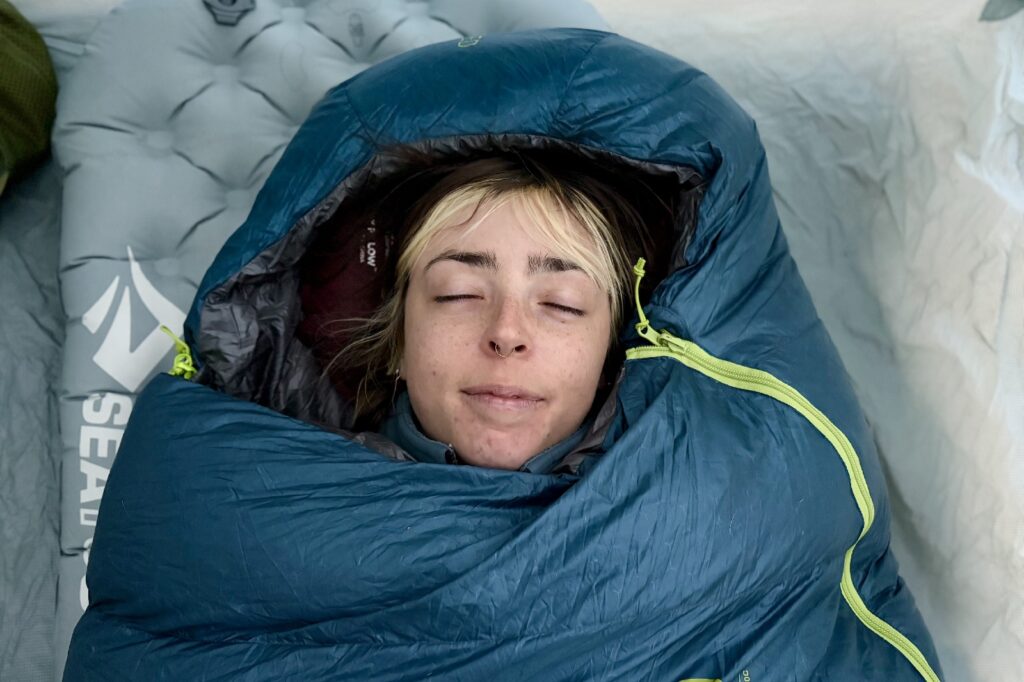 a shoulder up of from above of a hiker laying in a blue sleeping bag