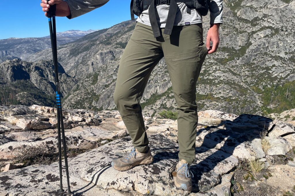A closeup of he front of green hiking pants in front of a rocky canyon.