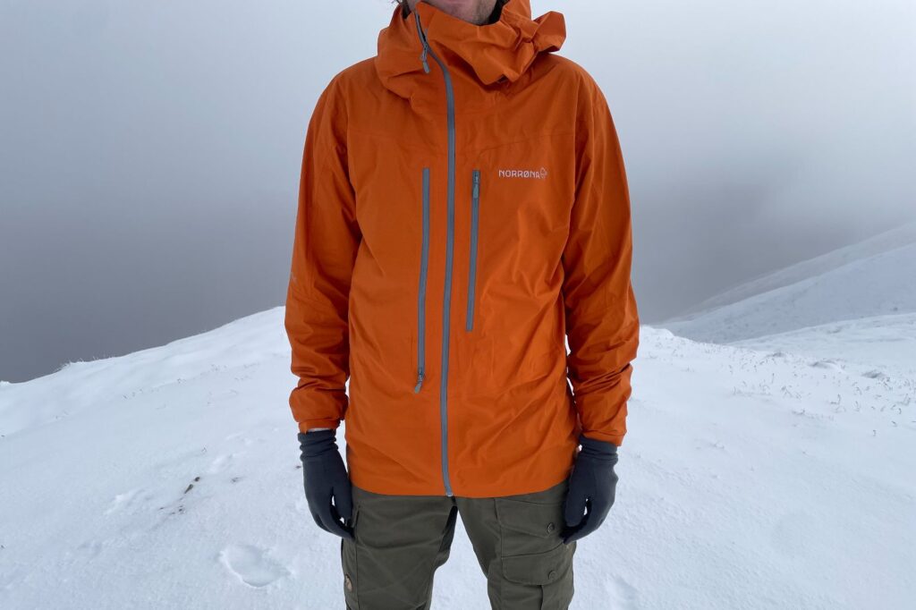 A front shot of an orange rain jacket showing the different pockets.