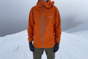 A front shot of an orange rain jacket showing the different pockets.
