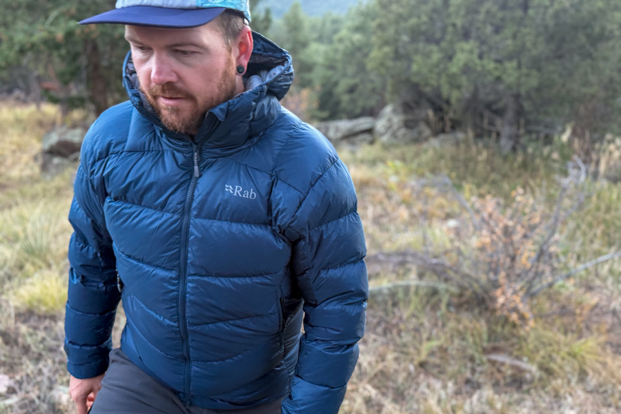 A person hikes uphill wearing the Rab Neutrino Pro jacket, demonstrating its mobility and comfort during active use.