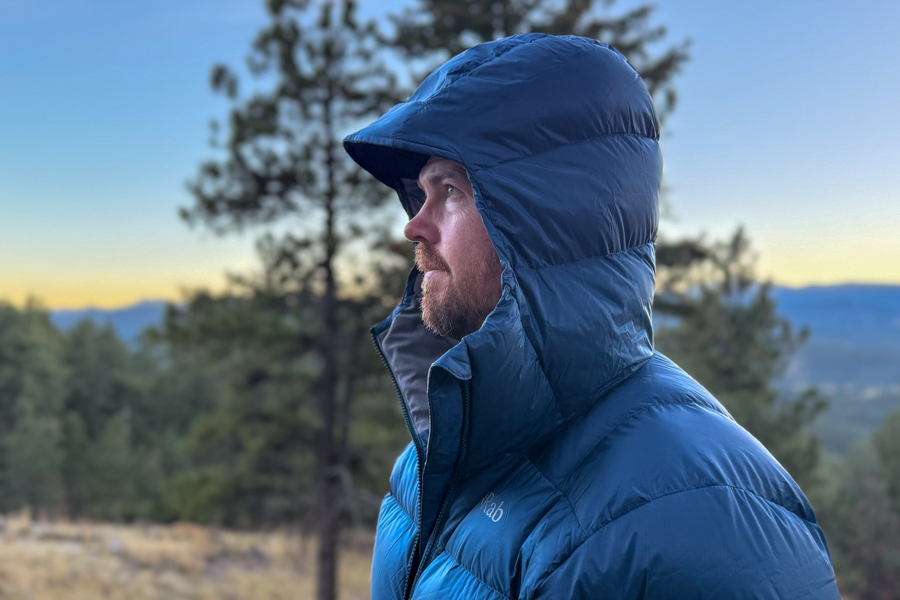 Side view of the Rab Neutrino Pro hood pulled up, showing its structured shape and full head coverage for cold conditions.