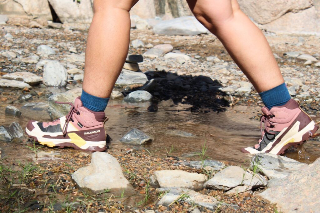 Hiker walking through a shallow stream wearing the Salomon X Ultra 5 GTX Women's Hiking Boots